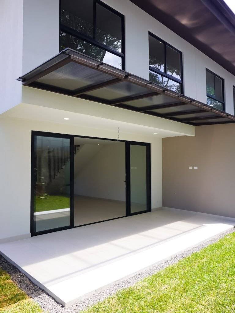 Patio trasero techado con puertas corredizas y ventanales, en casa de 385 Francosta, Barreal de Heredia.