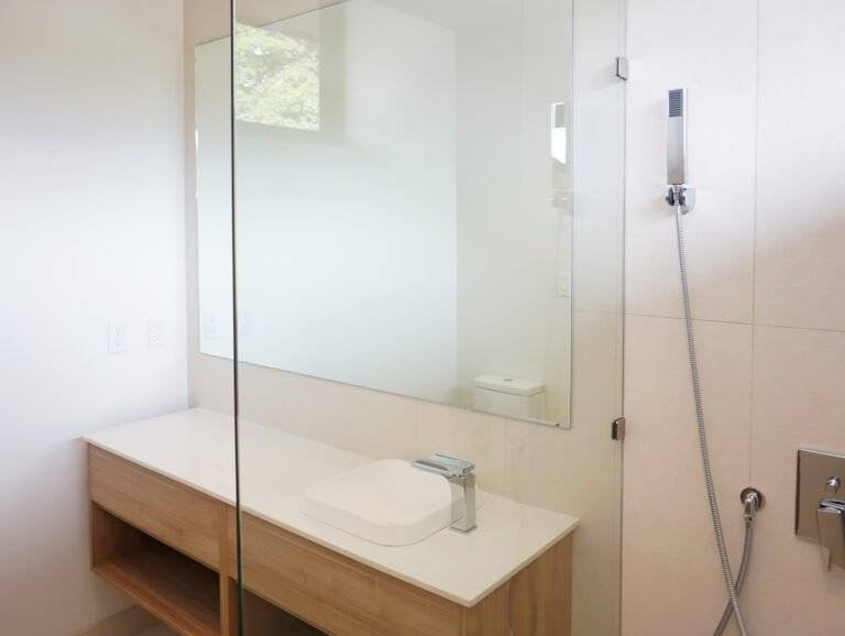 Baño moderno con mueble flotante de madera, lavamanos sobrepuesto y ducha con mampara de vidrio en 385 Francosta.